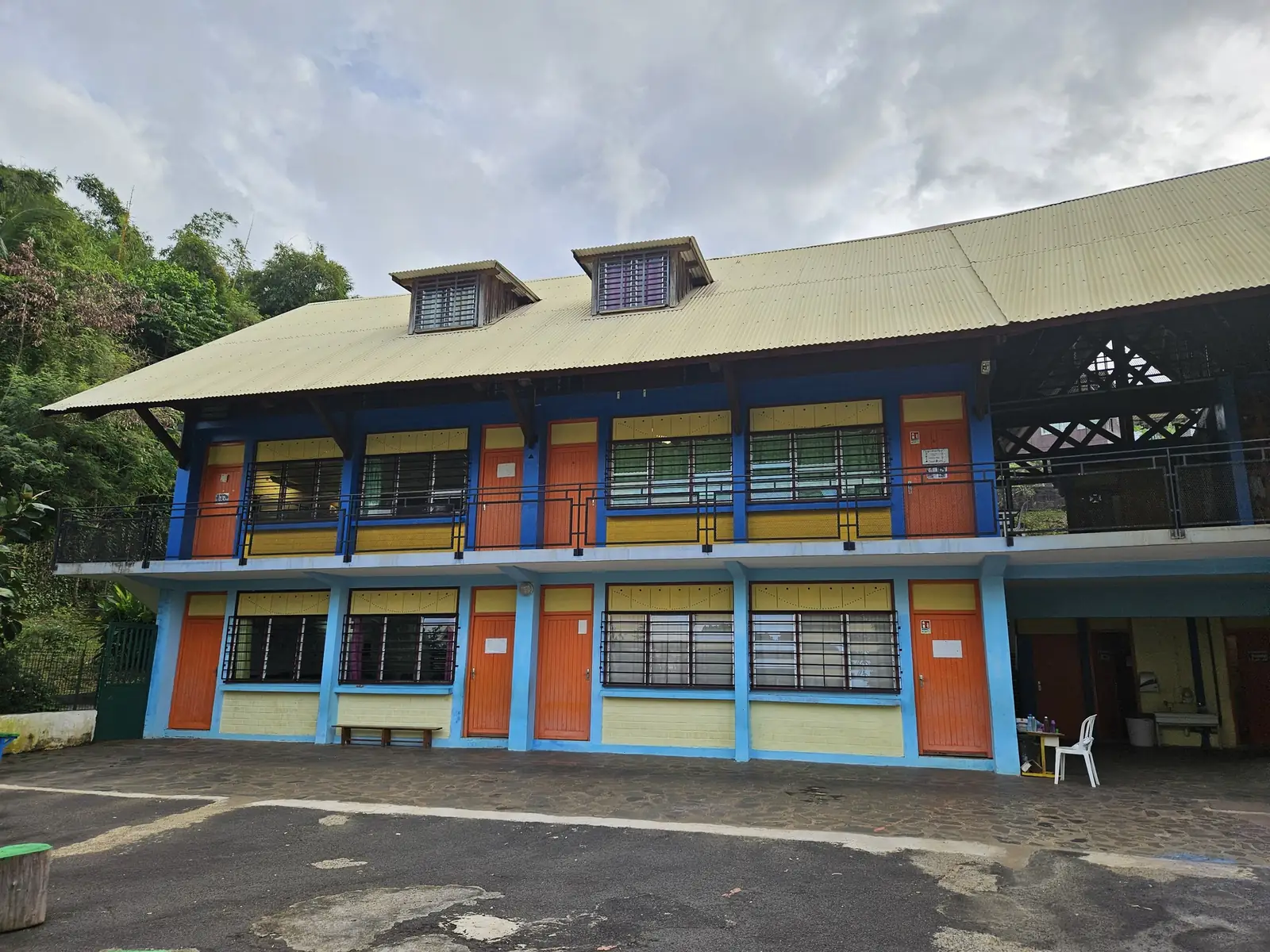 Façade colorée de l'école sur deux niveaux, portes orange et murs jaunes et bleus